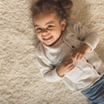 Happy little girl laying on soft plush carpet
